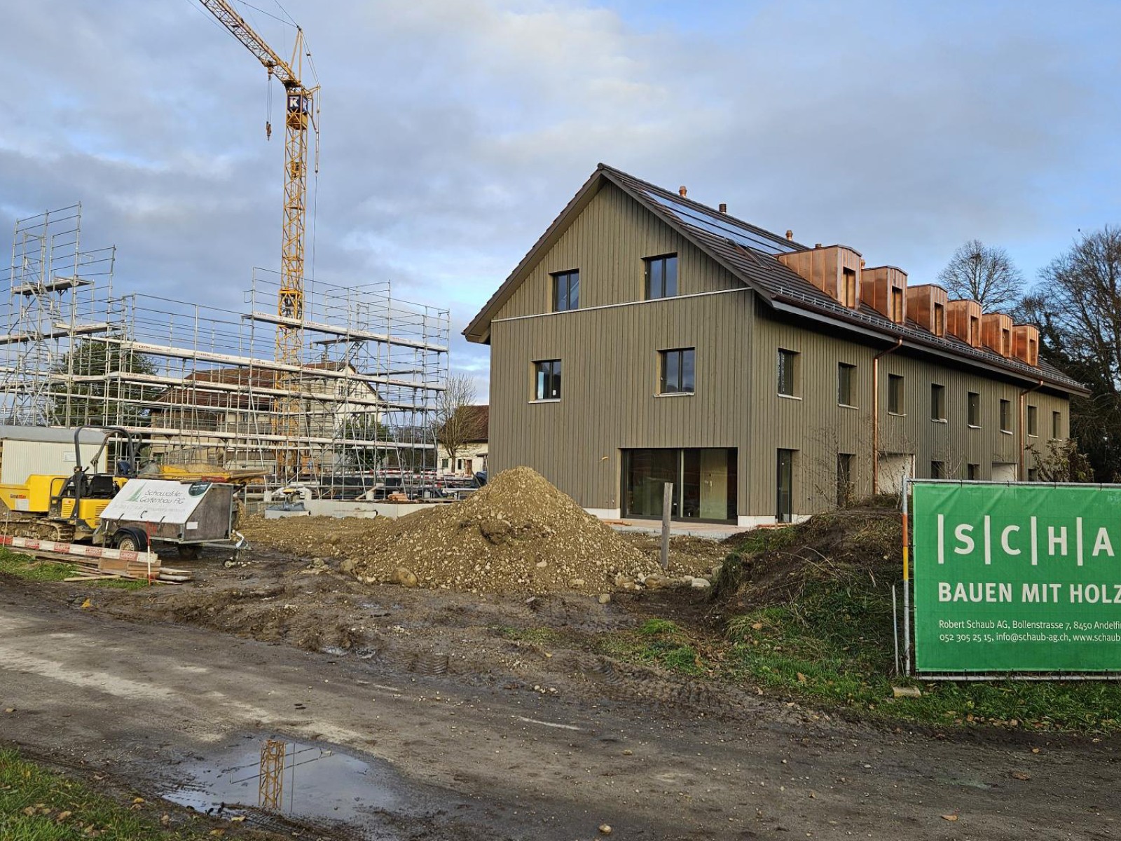 16.12.2024 Die Umgebungsgestaltung um die erste Bautetappe ist bereits weit gediehen… und das Gerüst für die Montage der nächsten zwei Reihenhäuser im Januar ist auch bereits gestellt.